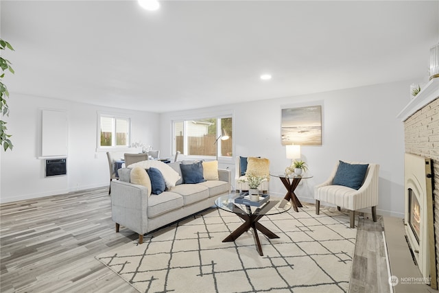 living room featuring light hardwood / wood-style flooring and a brick fireplace