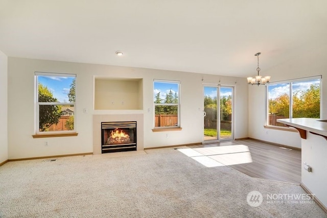13703 68th Avenue Ct E, Puyallup, WA 98373 - unfurnished living room featuring healthy amount of natural light, a chandelier, baseboards, and a fireplace with flush hearth