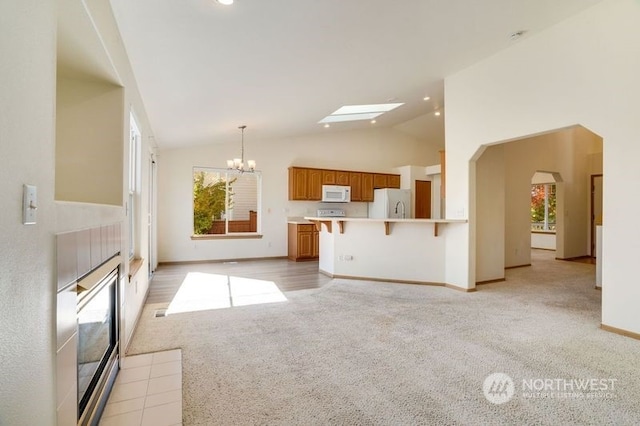 unfurnished living room featuring an inviting chandelier, lofted ceiling, light carpet, and plenty of natural light