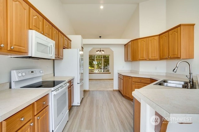 kitchen featuring white appliances, sink, light hardwood / wood-style floors, high vaulted ceiling, and an inviting chandelier