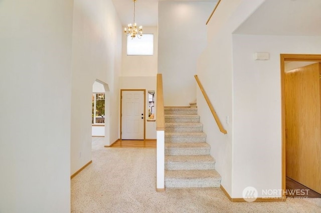 foyer with a notable chandelier, carpet floors, and a towering ceiling