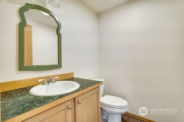 bathroom with vanity, toilet, and hardwood / wood-style flooring