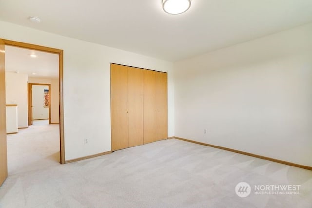 unfurnished bedroom with light colored carpet and a closet