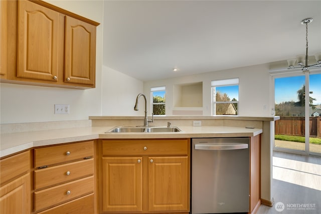 kitchen with a sink, a peninsula, light countertops, dishwasher, and a chandelier