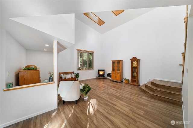 sitting room with hardwood / wood-style flooring, high vaulted ceiling, and a skylight