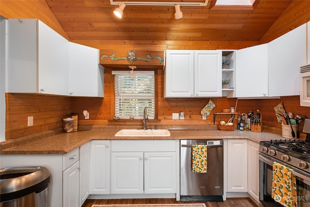 kitchen with white cabinets, track lighting, appliances with stainless steel finishes, vaulted ceiling, and sink