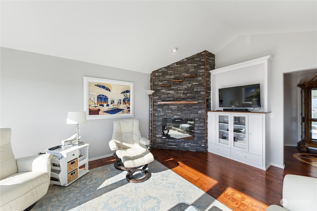 living room featuring dark wood-type flooring, vaulted ceiling, and a fireplace