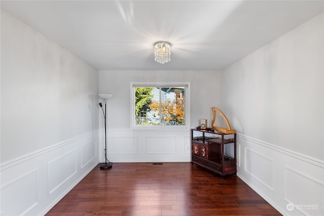 unfurnished room featuring dark wood-type flooring and a notable chandelier