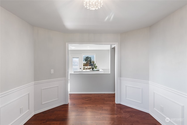 spare room featuring an inviting chandelier and dark hardwood / wood-style floors