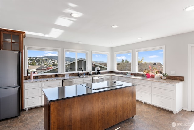 kitchen with a center island, appliances with stainless steel finishes, white cabinets, and plenty of natural light