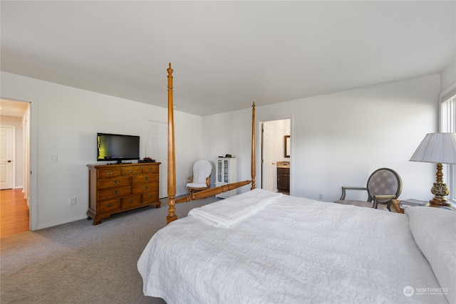 bedroom featuring ensuite bathroom and light colored carpet