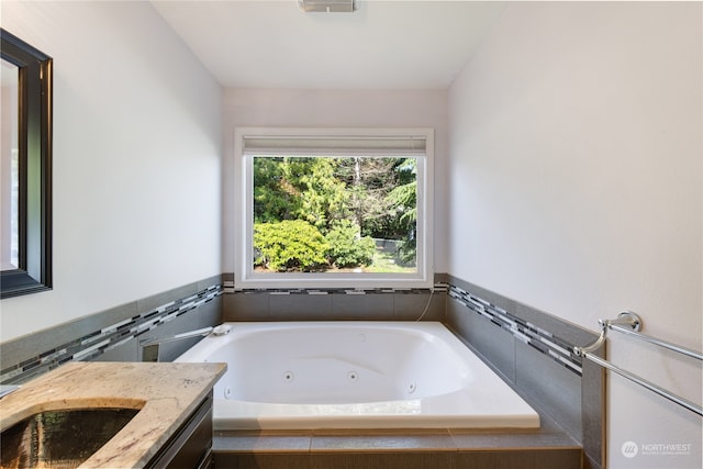 bathroom with sink and tiled bath