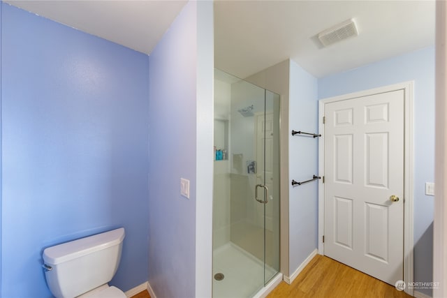 bathroom with hardwood / wood-style flooring, toilet, and an enclosed shower