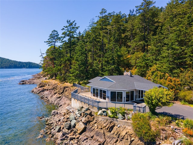 exterior space featuring a deck with water view and a sunroom