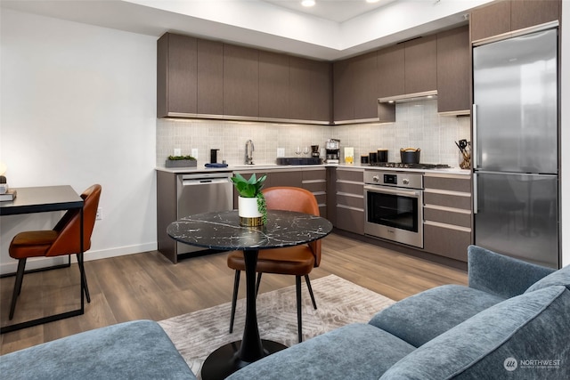 kitchen featuring gray cabinets, stainless steel appliances, light hardwood / wood-style floors, and tasteful backsplash