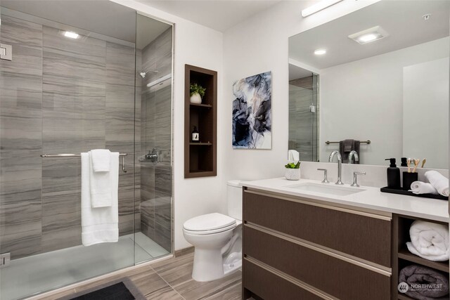 bathroom with vanity, a shower with shower door, and toilet