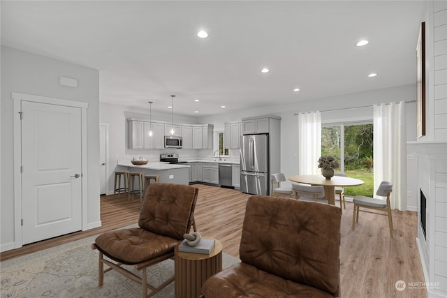 living room with sink, a brick fireplace, and light hardwood / wood-style floors