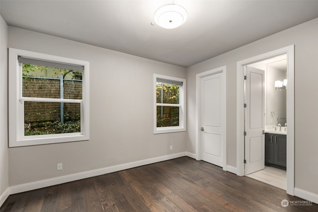 unfurnished bedroom with dark wood-type flooring, ensuite bathroom, and sink