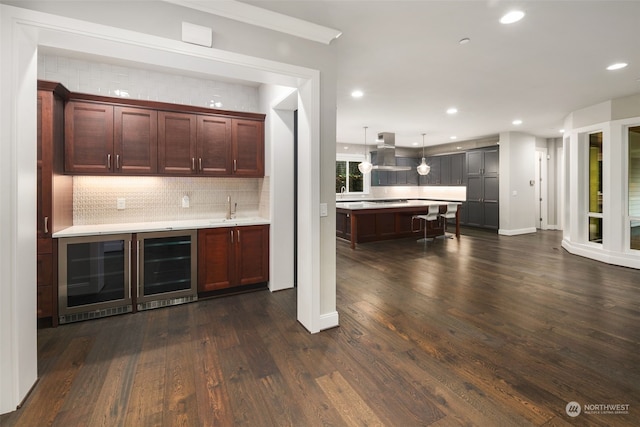 bar with tasteful backsplash, exhaust hood, dark hardwood / wood-style floors, pendant lighting, and sink