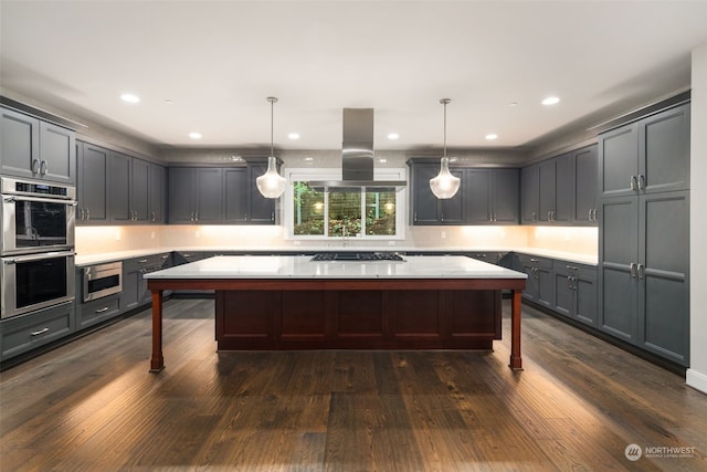 kitchen featuring island exhaust hood, hanging light fixtures, and dark wood-type flooring