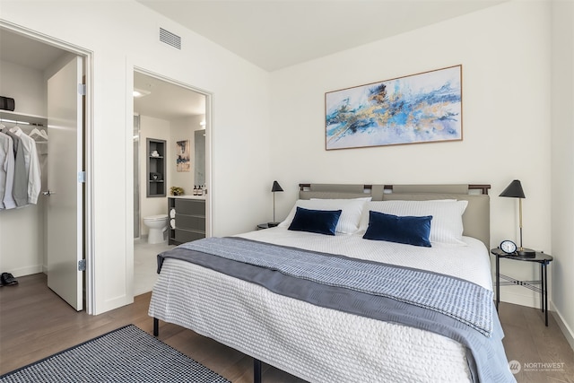 bedroom featuring a closet, ensuite bathroom, wood-type flooring, and a walk in closet