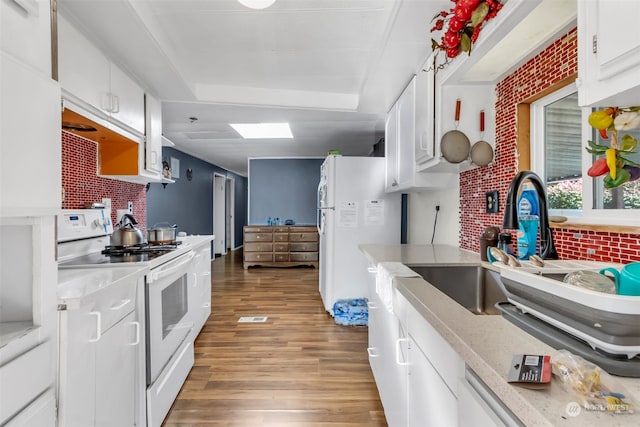 kitchen with white appliances, tasteful backsplash, sink, white cabinetry, and light hardwood / wood-style flooring