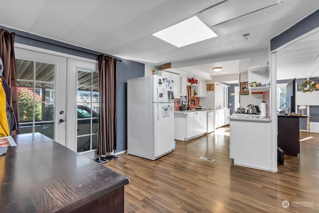 kitchen with french doors, dark hardwood / wood-style floors, kitchen peninsula, white cabinetry, and white fridge