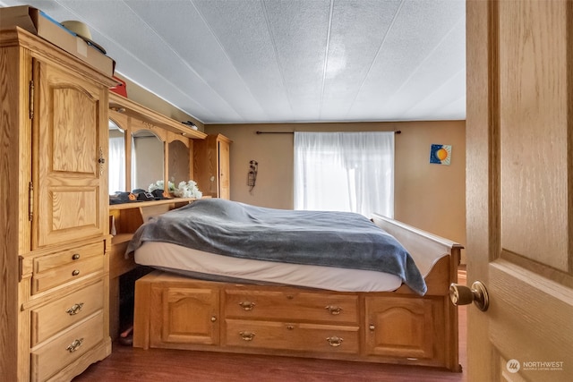 bedroom featuring a textured ceiling and dark hardwood / wood-style flooring