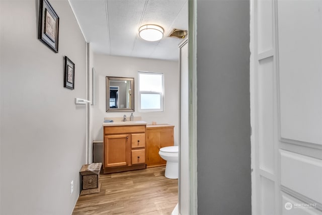 bathroom with vanity, hardwood / wood-style floors, toilet, and a textured ceiling