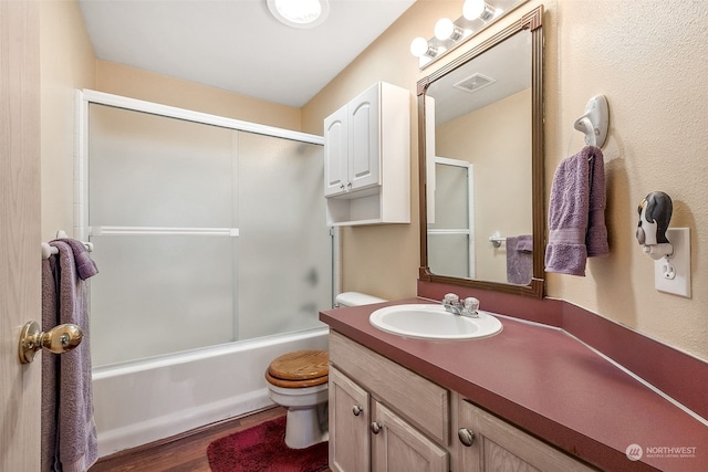 full bathroom featuring toilet, combined bath / shower with glass door, vanity, and wood-type flooring