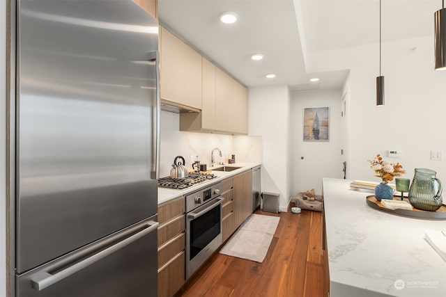 kitchen featuring tasteful backsplash, appliances with stainless steel finishes, dark wood-type flooring, sink, and light stone counters