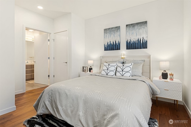 bedroom with connected bathroom and hardwood / wood-style floors