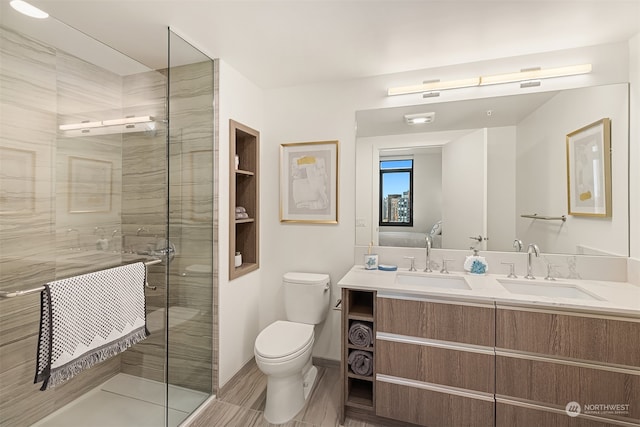 bathroom featuring a shower with door, vanity, and toilet