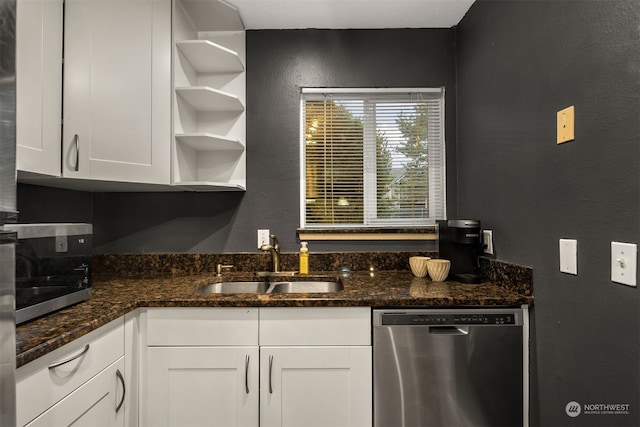 kitchen with white cabinets, dark stone countertops, stainless steel dishwasher, and sink