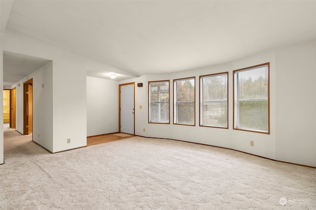 carpeted spare room with vaulted ceiling