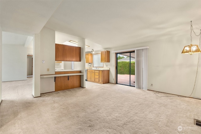 kitchen with light carpet, kitchen peninsula, decorative light fixtures, and vaulted ceiling