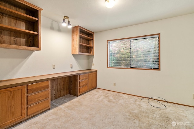 unfurnished office featuring light colored carpet and built in desk