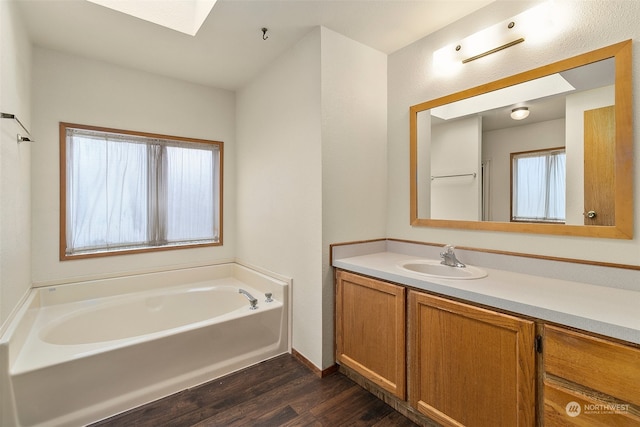 bathroom with a healthy amount of sunlight, vanity, hardwood / wood-style flooring, and a bathing tub