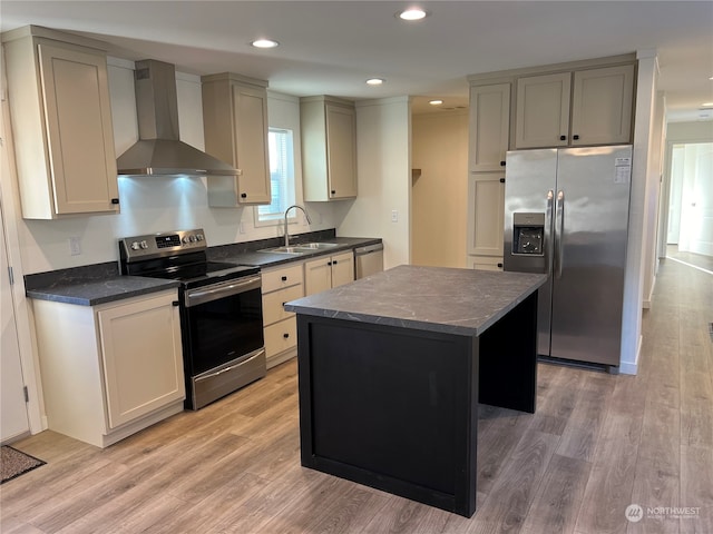 kitchen featuring wall chimney exhaust hood, sink, a center island, appliances with stainless steel finishes, and light hardwood / wood-style floors