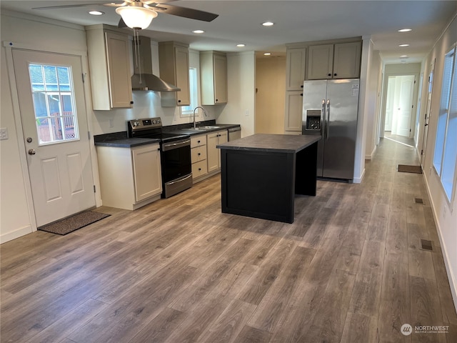 kitchen featuring stainless steel appliances, wall chimney range hood, a center island, and hardwood / wood-style floors