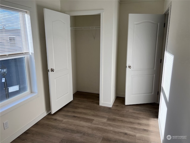 unfurnished bedroom featuring a closet and dark wood-type flooring