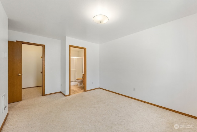 unfurnished bedroom with connected bathroom and light carpet