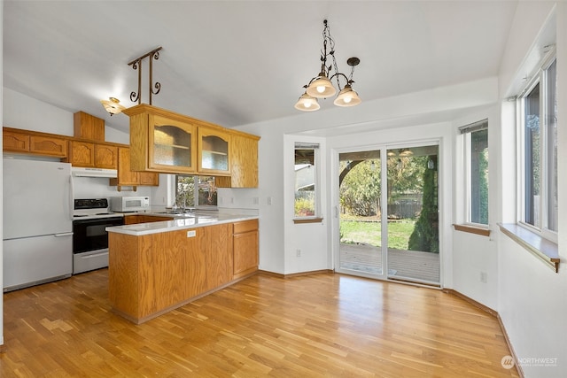 kitchen featuring white appliances, light hardwood / wood-style flooring, vaulted ceiling, and kitchen peninsula