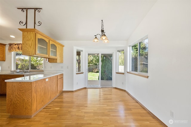 kitchen featuring sink, kitchen peninsula, light hardwood / wood-style floors, vaulted ceiling, and a notable chandelier