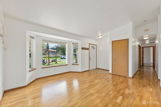 spare room featuring vaulted ceiling and light wood-type flooring