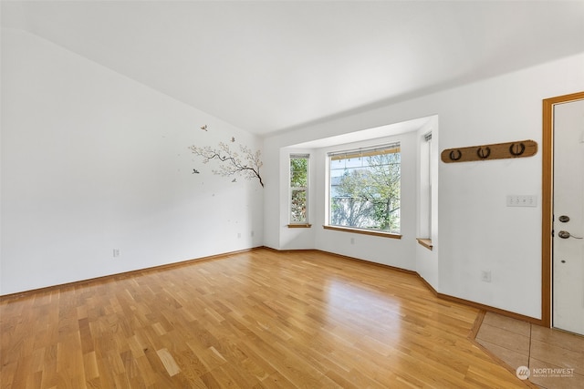 unfurnished room with lofted ceiling and light hardwood / wood-style flooring