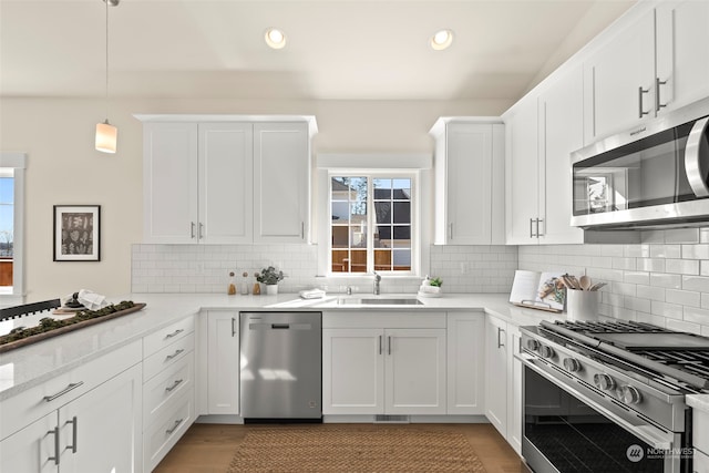 kitchen featuring white cabinets, tasteful backsplash, stainless steel appliances, and pendant lighting