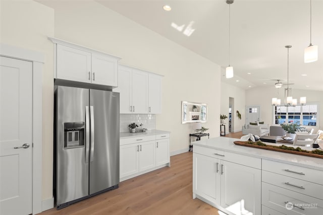 kitchen with vaulted ceiling, stainless steel fridge with ice dispenser, decorative light fixtures, white cabinets, and light hardwood / wood-style flooring