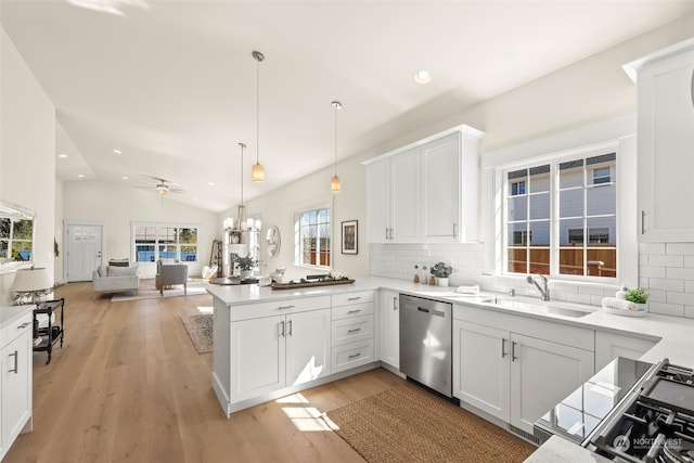 kitchen with sink, kitchen peninsula, lofted ceiling, stainless steel dishwasher, and decorative light fixtures