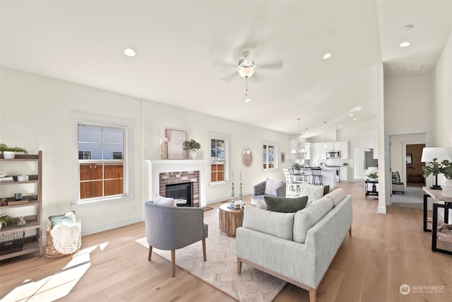 living room featuring lofted ceiling, a fireplace, light hardwood / wood-style floors, and plenty of natural light